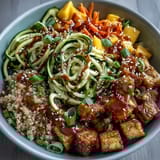 Freshly baked crispy tofu cubes glisten over a fluffy quinoa base, mixed with spiralized zucchini and carrots in an Easy Teriyaki Quinoa Bowl.