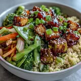 A close-up of a gluten-free vegan Quinoa Vegetable Teriyaki Bowl garnished with sesame seeds and fresh green onions for serving.
