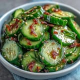 Crisp Asian cucumber salad with sesame and rice vinegar, tossed with fresh herbs and red pepper flakes for a tangy, spicy bite.