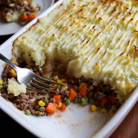 A close-up of a rustic, hot Shepherd's Pie ready for serving with visible steam.