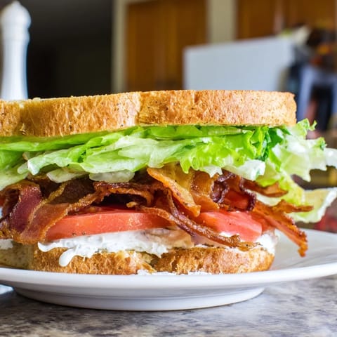 A perfect BLT sandwich: toasted bread holds layers of bacon, lettuce, tomato, and creamy mayo.