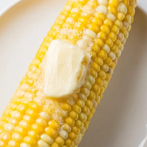 Steaming, buttery corn on the cob, perfectly grilled or boiled, ready for a delicious bite.
