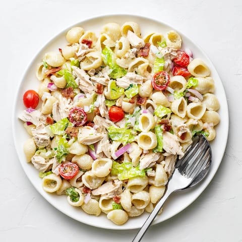 Hearty BLT Chicken Pasta Salad featuring crisp romaine, juicy cherry tomatoes, and crumbled bacon tossed with tender pasta shells.
