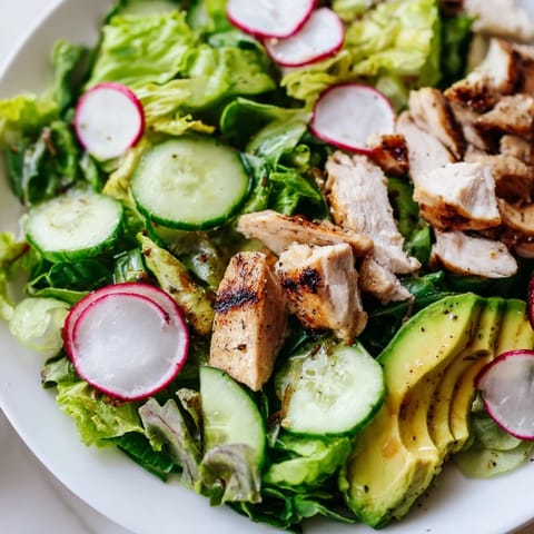 Freshly grilled chicken slices rest atop a vibrant bed of Spring Detox Chicken Salad with crisp cucumber and radish, drizzled with zesty lemon vinaigrette.