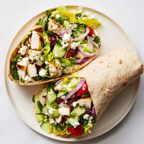 A Greek Lemon Chicken Salad Wrap wrapped in foil with a side salad, perfect for an easy Mediterranean lunch.