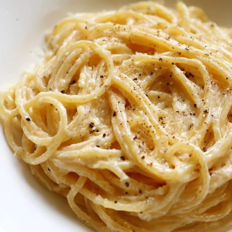 A close-up of Spaghetti Cacio e Pepe reveals a silky, peppery sauce clinging to al dente pasta, served with a simple green salad.