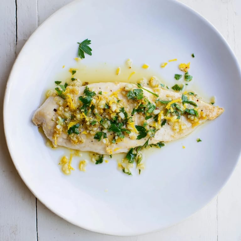 Juicy Lemon Pepper Chicken breasts lifted from a hot skillet with tongs, steam rising from the seared, golden exterior.