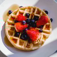 Fluffy golden waffles piled high, ready to be enjoyed with fresh seasonal berries and syrup.