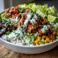 Golden, crispy-edged carnitas piled high on fluffy rice with black beans and corn in a Carnitas Burrito Bowl.