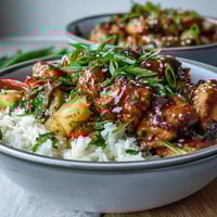 Glazed teriyaki chicken and rice bowl with fluffy rice, crisp stir-fried veggies, and fresh pineapple garnish.
